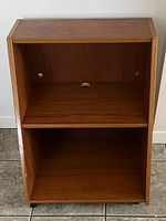 Front view of teak veneer TV stand showing two open shelves and cable holes in back panel.