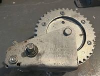 Close-up photo of the metal T1000A trailer winch showing cogwheel and ratchet mechanism with stamped model and capacity information.