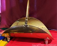 Front angled view showing the curved brass basket body, handle, and lion paw feet