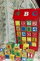 Photo showing red wooden caddy holding colorful wooden blocks arranged alphabetically and by numbers.