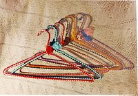 Six colorful metal hangers crocheted in different colors, arranged in a row showing variety of yarn colors and flower decorations.