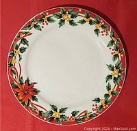 Top-down view of the round porcelain Christmas platter showing the festive holly and poinsettia design on a beige background with a red rim.