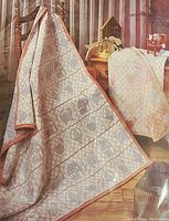 Quilt draped over a rack showing soft pastel tones in woven country and floral motifs with houses and other designs.