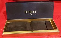 Top view of the brown leather wallet inside Buxton branded box showing card slots, coin pocket, and bill compartments.