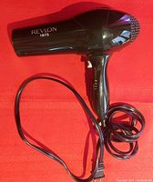 Side view of black Revlon 1875 turbo hair dryer showing the model branding and attached power cord.