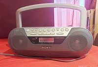 Front view of grey Sony Mega Bass boombox showing speaker grills, buttons, display, and power cord