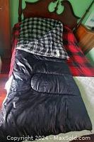 Sleeping bag laid on a twin XL bed, showing flannel plaid interior lining and full size.