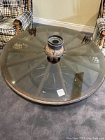 Top-front view of round tinted glass top and wagon wheel base with center knob.