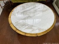 Top-down view of the round marble tabletop showing the white and gray veining and segmented gold leaf trim around the perimeter.