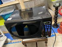 Front view of black Danby Designer microwave oven showing digital control panel and door with curved window.