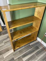 Front-facing view of the oak shelving unit showing the three shelves and natural wood grain finish.