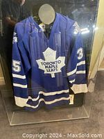 Front view of plexi display case showing full blue Maple Leafs jersey with white stripes and #35.