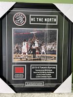 Framed photo featuring Toronto Raptors game tip-off, team logo, team slogan 'We The North', and court floor piece in bottom left.