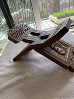Side view of wooden folding chair showing carved word 'Honduras' and folding mechanism.