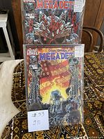 Two comic books from Chaos Comics featuring Megadet, issues #2 and #4, placed standing upright on a patterned surface with price stickers visible.