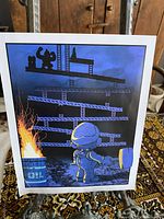 Donkey Kong 8x10 art print standing on an ornate easel, showing the character holding a hammer and Donkey Kong on platforms with a burning oil barrel on the left.