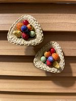 Pair of triangular hand woven earrings with clusters of colorful beads on a wooden background.