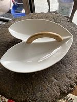 Top view of the white ceramic serving dish with a wooden handle showing the asymmetrical two-section design and smooth finish.
