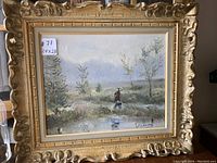 Frontal image showing the entire framed oil on canvas painting, featuring a landscape with a figure by water and trees surrounded by an ornate gold frame.