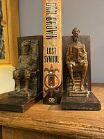 Front view of both carved wooden bookends holding a book between them on a wooden surface.