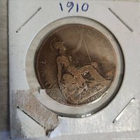 Obverse side of 1910 penny coin in protective holder, showing seated Britannia figure and dated 1910