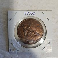 Front view of 1920 penny with seated Britannia design in cardboard holder labeled 1920