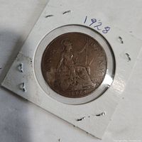 Front of 1928 one penny coin showing seated Britannia design and date.