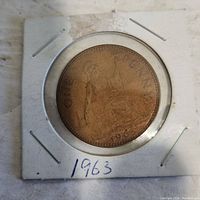 1963 One Penny coin in a cardboard and plastic protective holder, showing the seated Britannia side with year 1963 and the text 'ONE PENNY'.