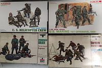 Four boxed 1/35 scale military model kits including U.S. Helicopter Crew, U.S. Marine (Tet Offensive 1968), German Sappers, and Sprecher Goliath Assault Engineers, arranged flat and viewed from above.