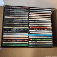 Photo showing the full boxed stack of music CDs with visible titles spanning classical piano, rock, pop, country, and Polish folk music.