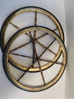 Front view of two vintage metal wheels with brass spokes, showing age and wear.