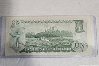 Reverse side of the 1973 Canadian one dollar bill showing Parliament buildings and denomination.