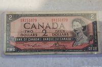 Front view of 1954 Canadian two dollar banknote showing serial number and Queen Elizabeth II portrait.