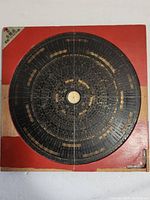 Full view of the Feng Shui compass showing the circular dial with multiple Chinese character rings on a red wooden base.