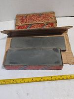 Photo of the two sharpening stones placed inside the original cardboard box showing the top and side of each stone and the outer packaging.
