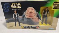Box front view showing Jabba the Hutt and Han Solo figures inside a window box with Star Wars branding and logos.