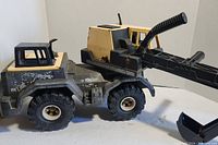 Side view showing yellow and black cab, worn paint, large black tires, and articulated chute/arm on truck.