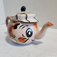 Side view of Wade ceramic teapot shaped and painted as a golfer’s face with a cap lid and nose-shaped spout