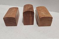 Three wooden boxes with curved magnetic lids lined up horizontally on a white surface.