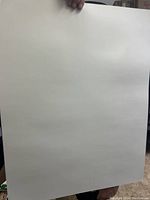 Close-up of a single white bristol board sheet held upright, showing its smooth, clean surface and thickness.