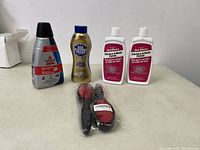 Cleaning products displayed on table: 2 bottles of Gel-Gloss Kitchen & Bath Polish, 1 bottle of Bar Keepers Friend cleaner, 1 bottle of Bissell Spot & Stain cleaner, and a pair of cleaning gloves.