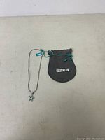 Starfish pendant necklace on chain alongside black branded pouch with green drawstrings, pouch marked EFFY