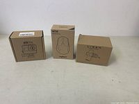 Three boxed electronic items on a table: FitStill action camera, Logitech M720 mouse, and Lisen phone holder.