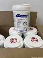 Six white plastic containers with Diversey Accel INTERvention label stacked in a cardboard box, showing product name and active ingredient.