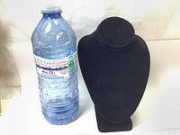 Photo showing black velvet necklace jewelry display mini stand next to a bottled water for size comparison.