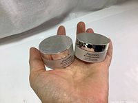 Two round jars of Shiseido Bio-Performance Glow Revival Cream each 18ml in palm, showing silver caps and white containers with labels.