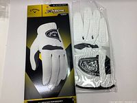 Front packaging of golf glove showing brand and model, white glove visible
