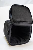 Open view of the soft black camera lens case showing padded interior and zippered flap.