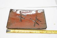Top view of the rectangular clay plate showing reddish-brown surface with black bamboo design and glaze.