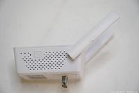 Side view of white wireless mini router with ventilation holes, small button, and one antenna angled upward.